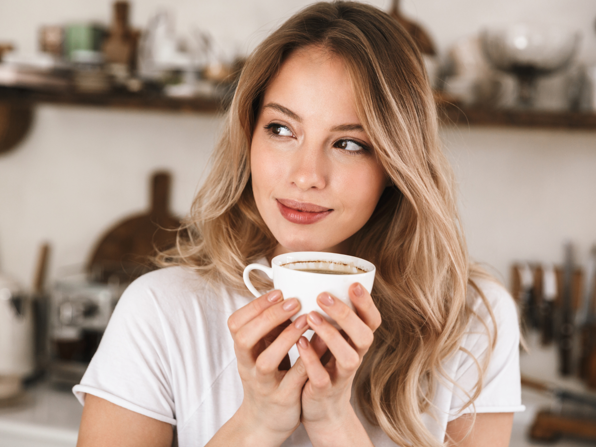 Woman Happily Holding White Cup Of Organic Italian Roast Coffee In Kitchen