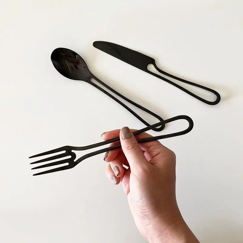 Holding Minimalist Cut Out Handle Stainless Steel Fork With Other Matching Modern Black Silverware Pieces