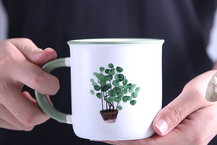 Holding A Painted Plants Watercolor Style Ceramic Mug With Potted Eucalyptus Houseplant