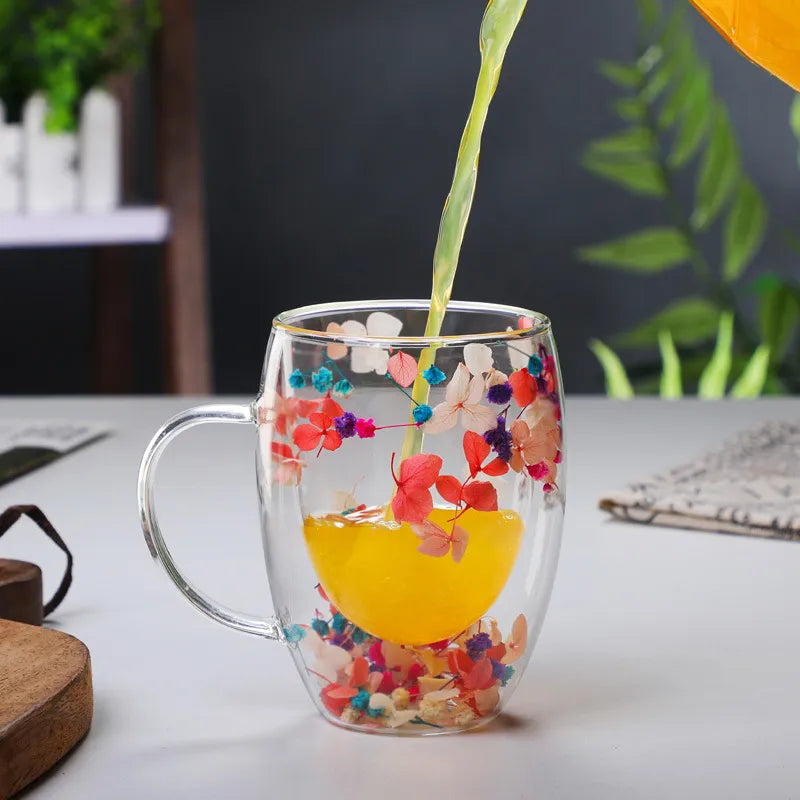 Pouring Orange Juice Drink Into Glass Mug With Real Flowers In It