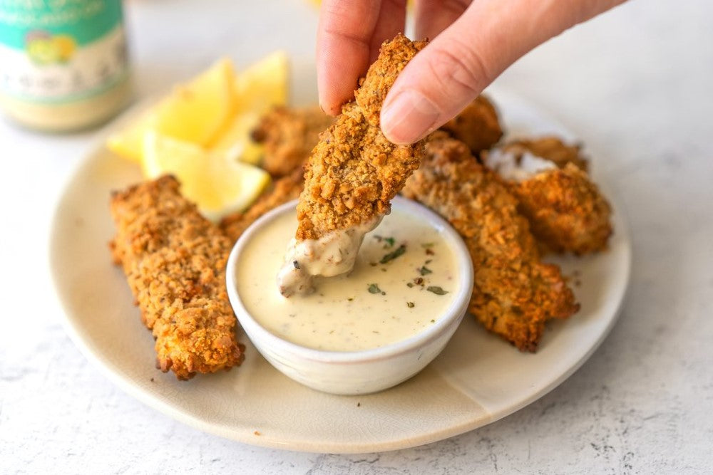 Dipping Healthy Air Fryer Fish Sticks In Tartar Sauce From Primal Kitchen