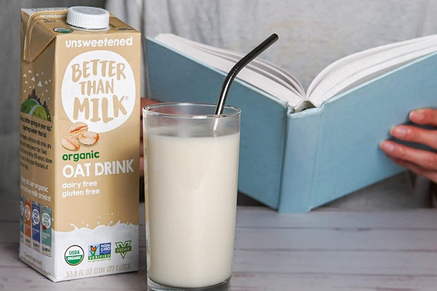 Glass Of Oat Milk Beverage Person Reading Book And Box Of Unsweetened Better Than Milk Organic Oat Drink 