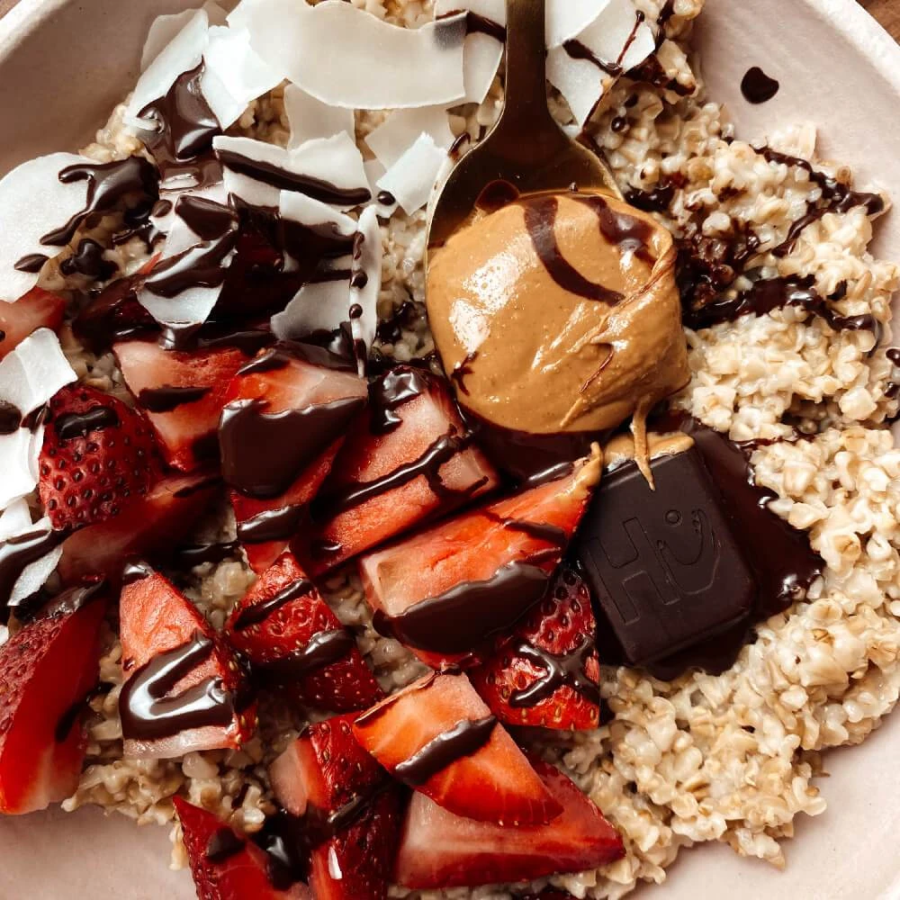 Delicious Bowl Of Breakfast Food Topped With Coconut Fresh Strawberries Nut Butter And Hu Chocolate