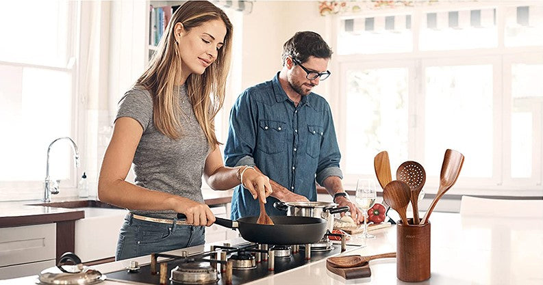 Happy Couple Cooking Together Using Stylish Chef Utensils Teak Wood Kitchen Tools In Non-Stick Pan