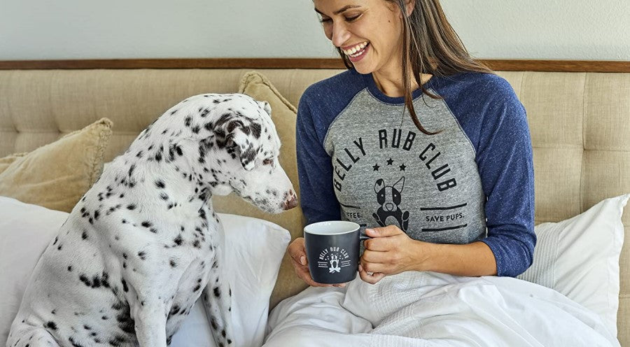 Woman Sitting On Bed Drinking Organic Coffee With Dalmatian Dog And Belly Rub Club Apparel From Grounds & Hounds Coffee