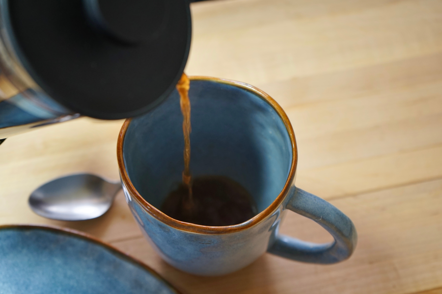 French Press Pouring Organic Coffee Into Blue Mug