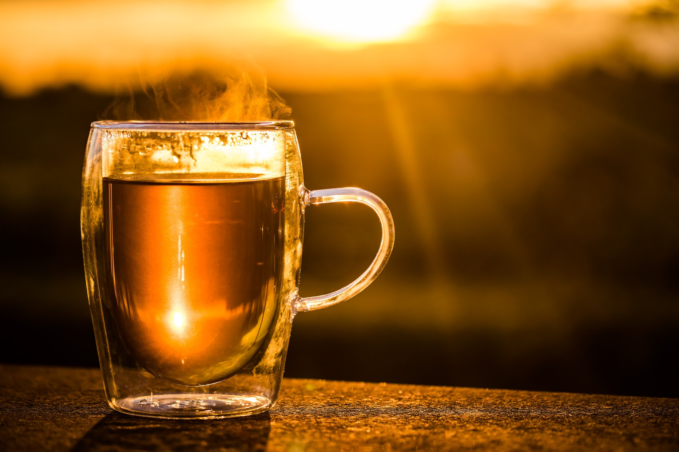 Golden Cup Of Hot And Fresh Steeped Tea In Clear Mug Outside In Golden Hour Lighting