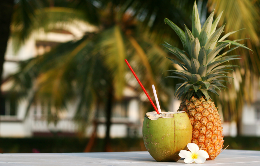Green Coconut With Fresh Pineapple And Flower Outdoors In Tropical Setting With Palm Trees
