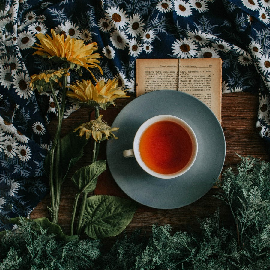 Cup Of Herbal Tea With Sunflowers Something To Read And A Floral Tablecloth