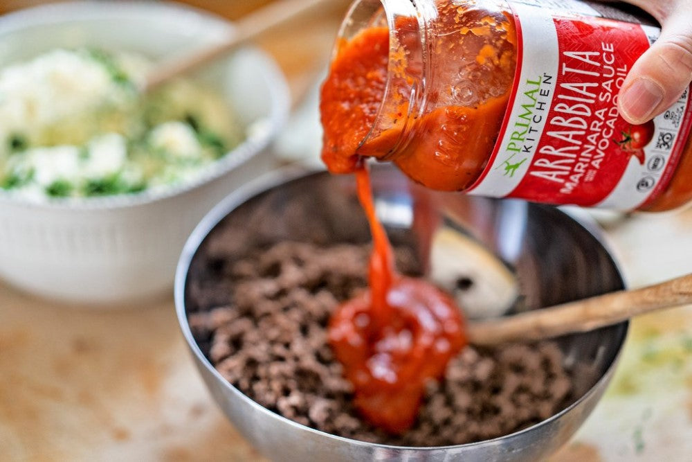Pouring Arrabbiata Sauce Into Keto Spicy Lasagna Recipe Primal Kitchen Marinara