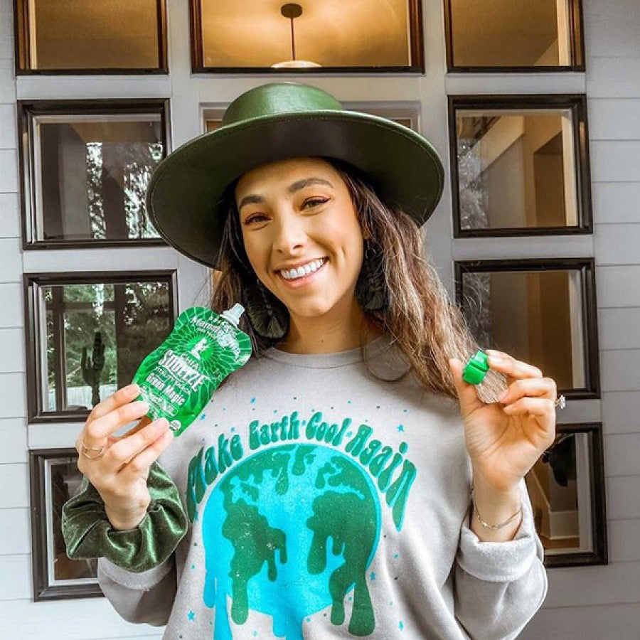 Happy Woman In Hat And Make Earth Cool Again Sweatshirt Enjoying A Green Magic Mamma Chia Squeeze Pouch