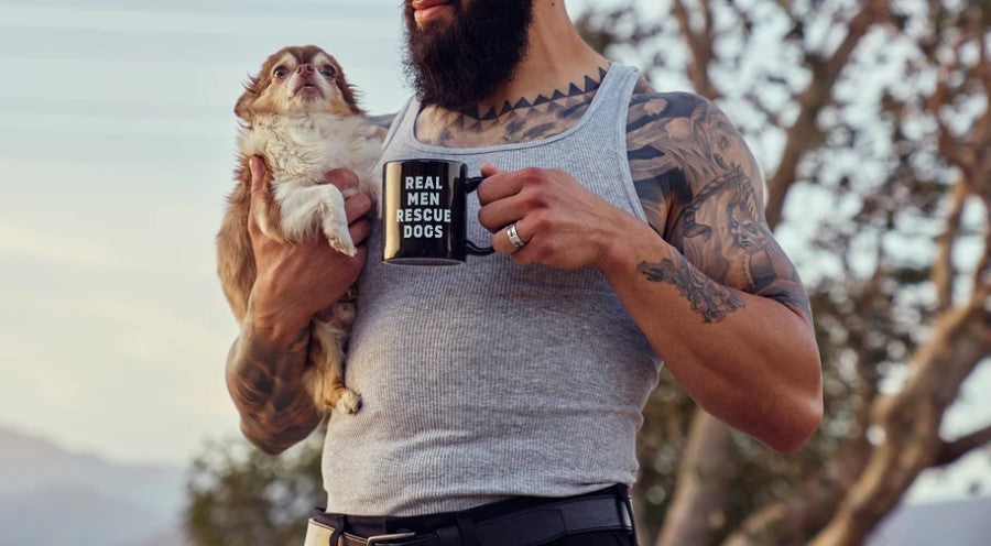Tattooed Man With Beard Holding Little Dog And Real Men Rescue Dogs Coffee Mug Outdoors