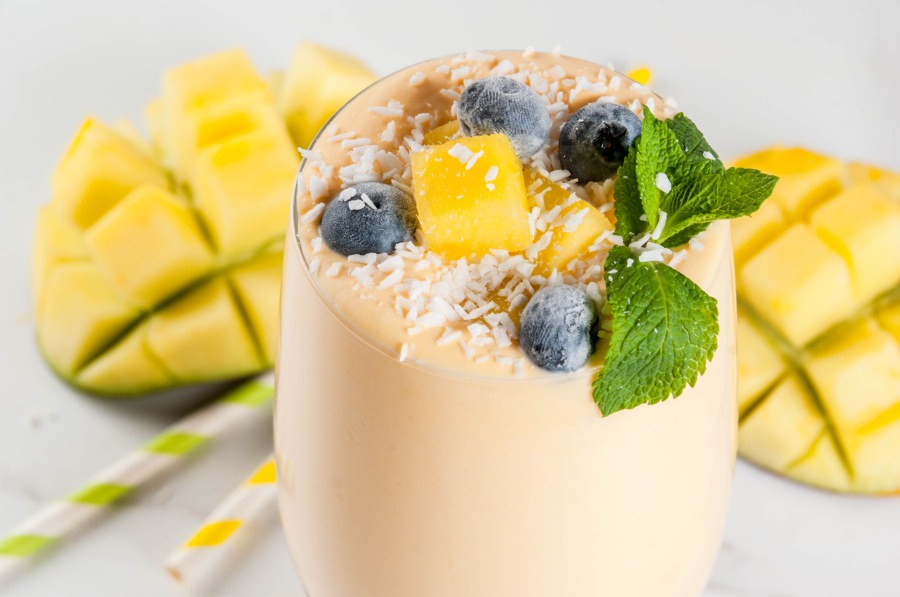 Mango Smoothie Made With Coconut Water Topped With Shredded Coconut Blueberries Mint And Mango Cubes