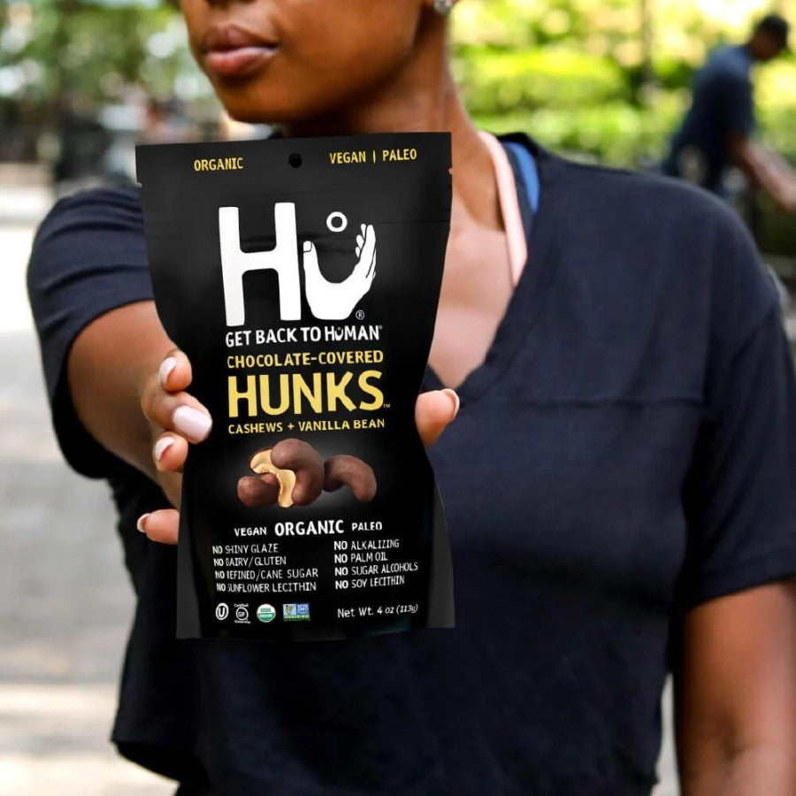Person Holding Up A Bag Of Hu Hunks Organic Chocolate Covered Cashews