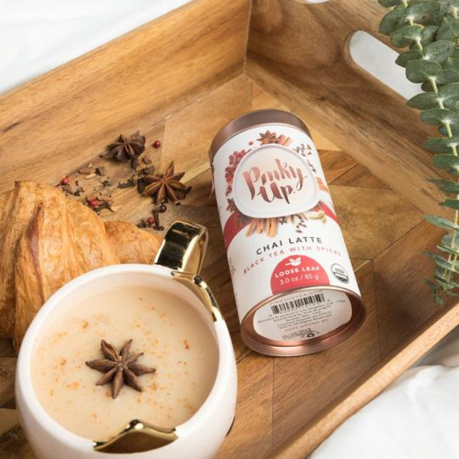 Pinky Up Spiced Black Tea Chai Tea Latte Topped With Star Anise Pod On Wooden Tray With Pastry