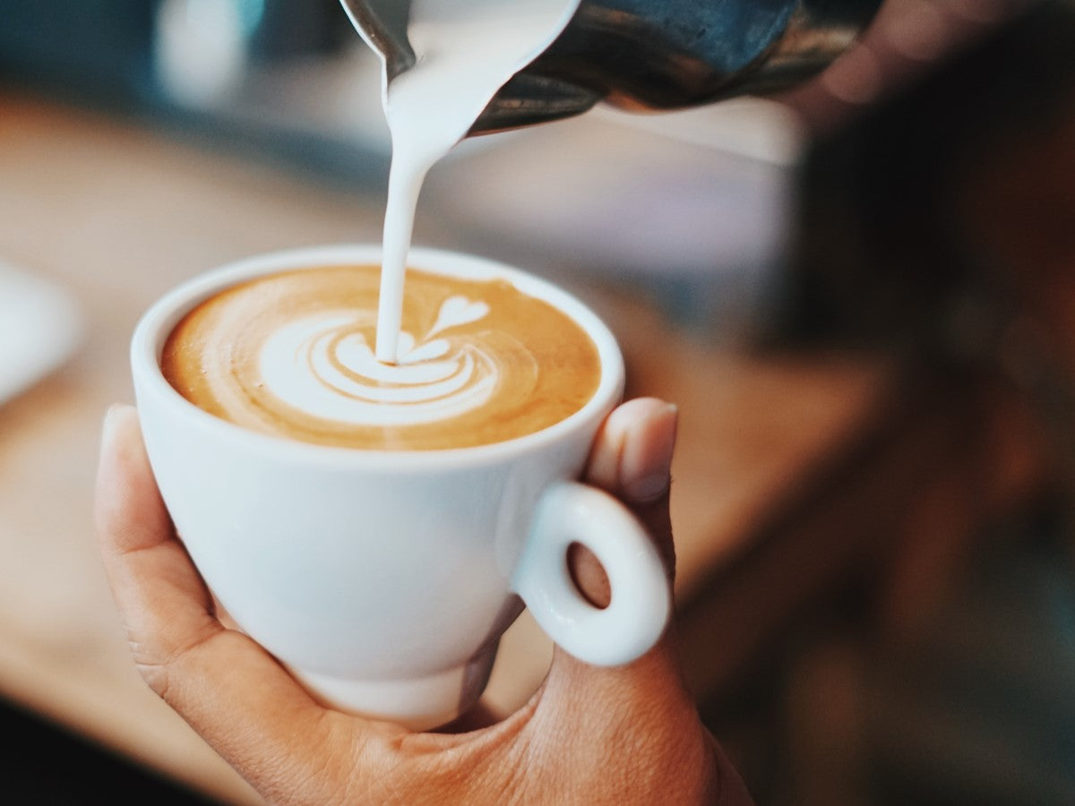 Pouring Frothy Milk Into Latte In White Cup