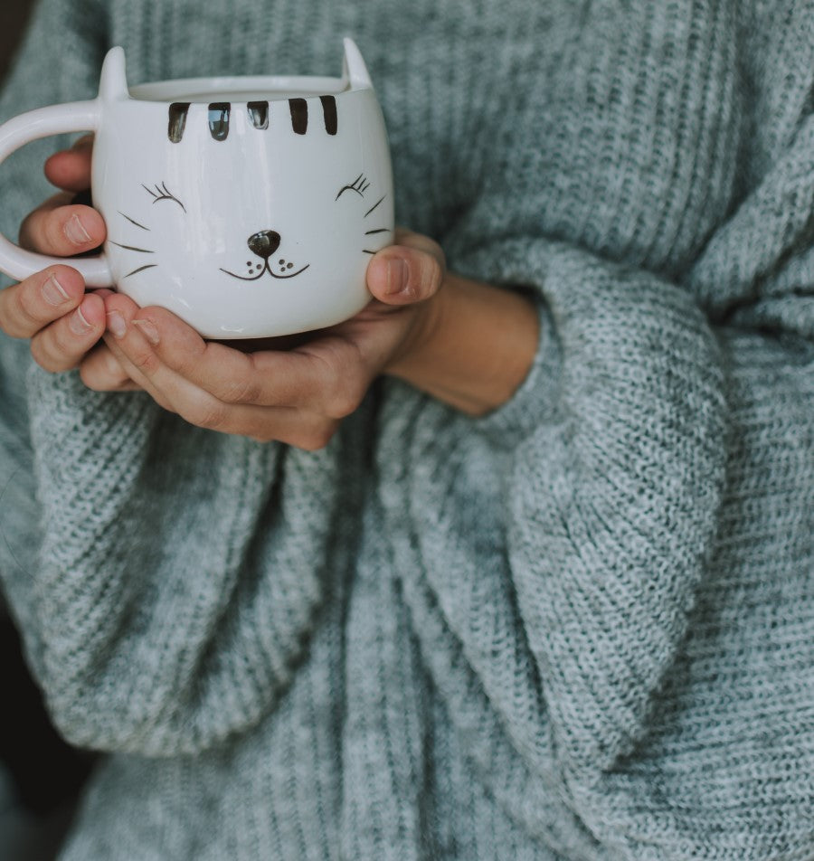 Smiling Cat Mug Being Held By Woman In Grey Oversized Sweater