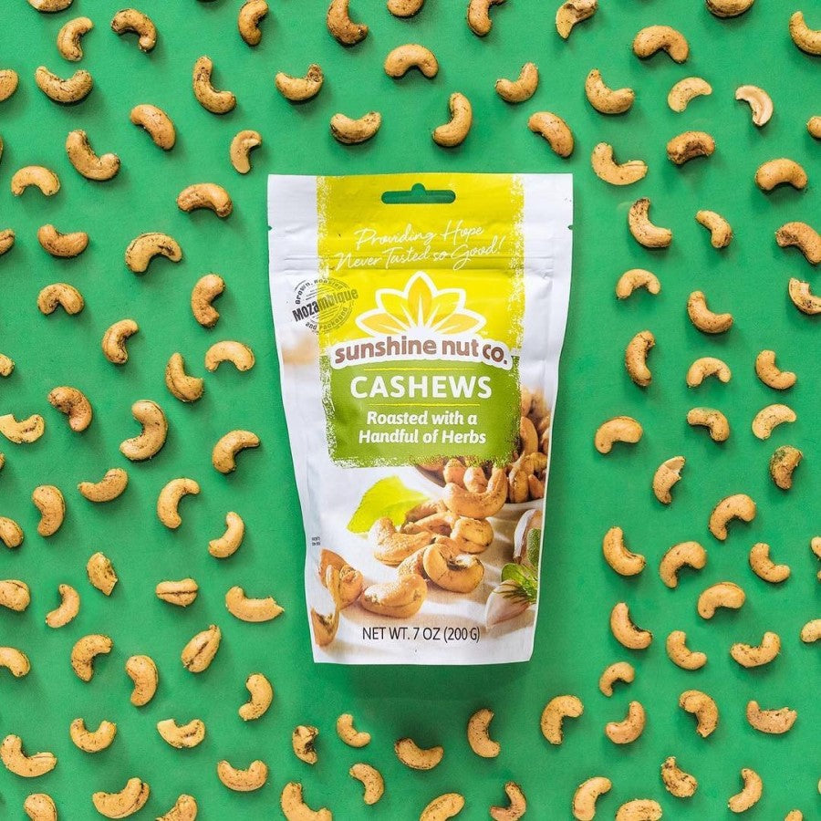7 Ounce Bag Of Sunshine Nut Co. Cashews Roasted With A Handful Of Herbs On Green Background With Flavorful Cashew Nuts Coated In Herbs