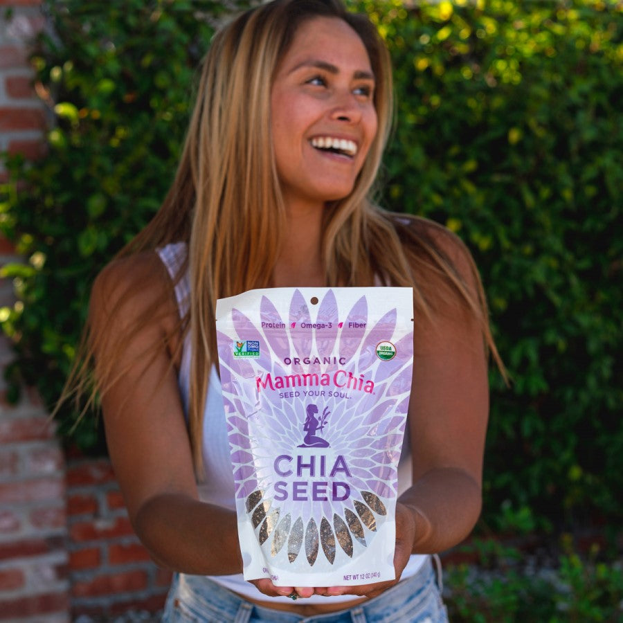 Happy Woman Outdoors Holding White Bag Of Black Chia Seed Organic Mamma Chia