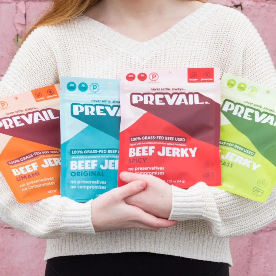 Woman Holding 4 Flavors Of Prevail Grass-Fed Beef Jerky Umami Original Spicy And Lemongrass