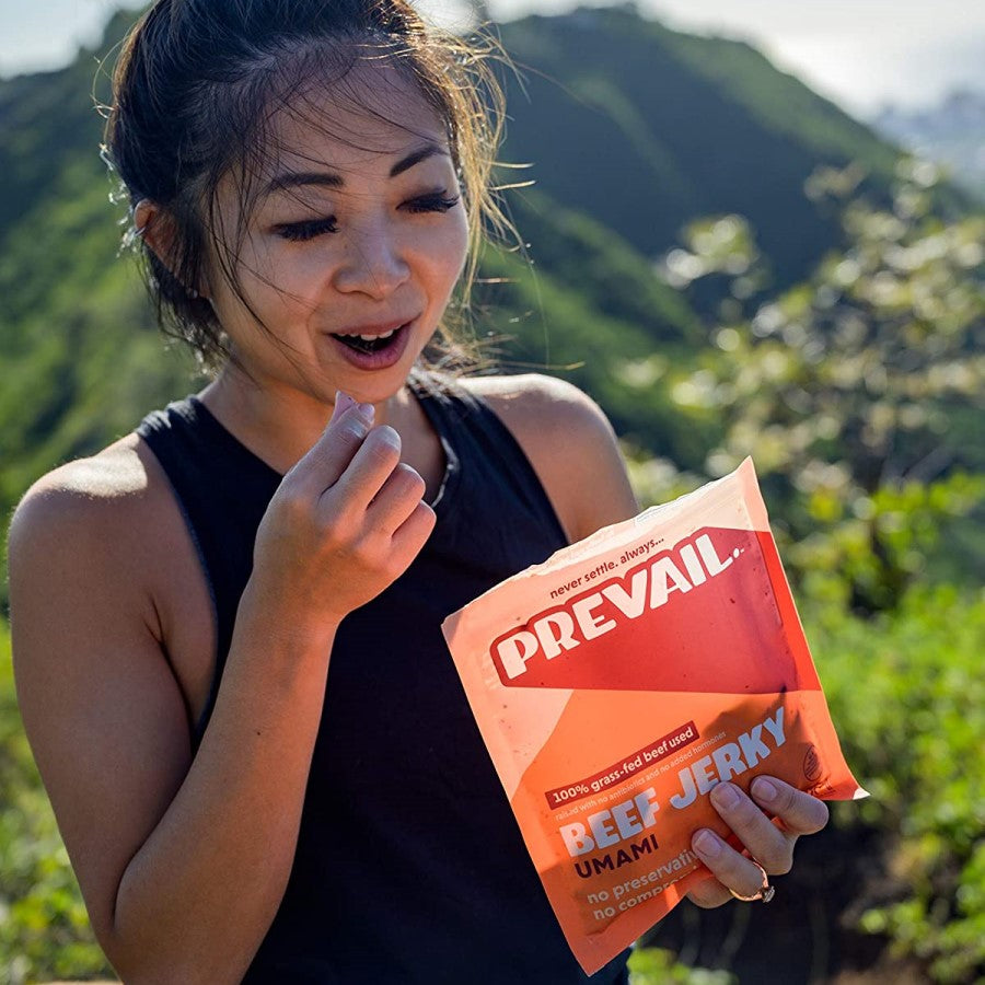 Woman Outdoors Hiking Snacking Protein Rich Umami Beef Jerky From Prevail