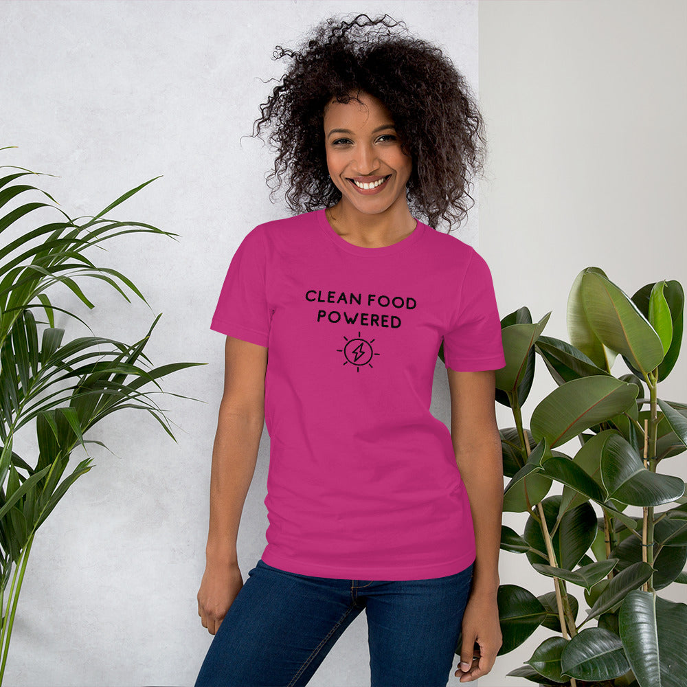 Happy Woman Standing By Plants Wearing Clean Food Powered Tee Shirt In Berry From Terra Powders
