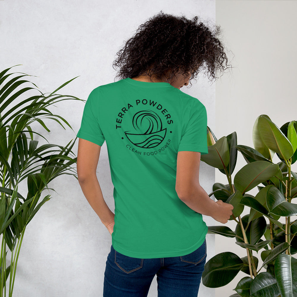 Woman Standing By Plants Wearing Shirt From Terra Powders Back Of Clean Food Powered Short Sleeve Shirt In Kelly Green With Terra Powders Logo