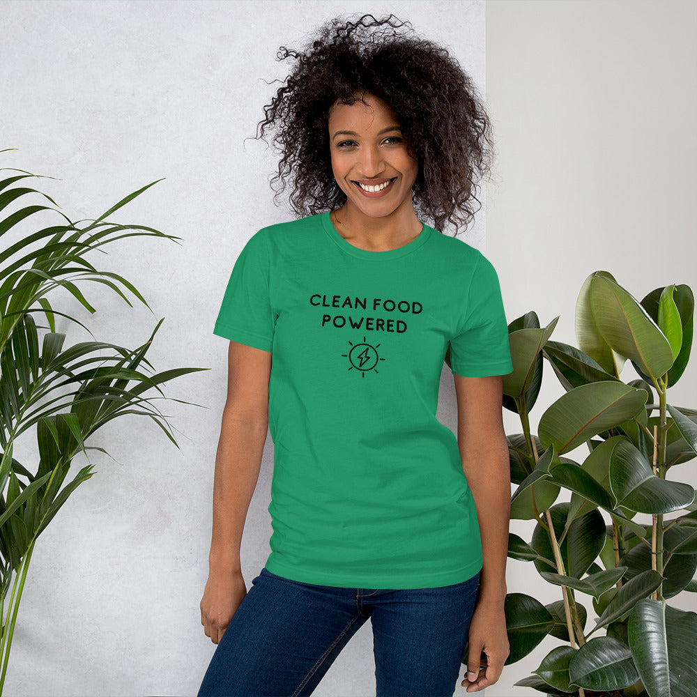 Happy Woman Standing By Plants Wearing Clean Food Powered Tee Shirt In Kelly Green From Terra Powders